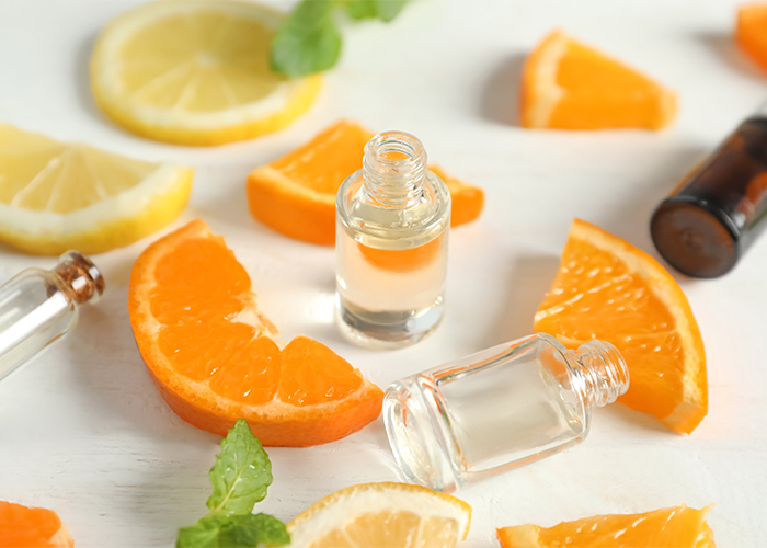 Clear bottles filled with citrus essential oil with slices of orange and lemon on a table