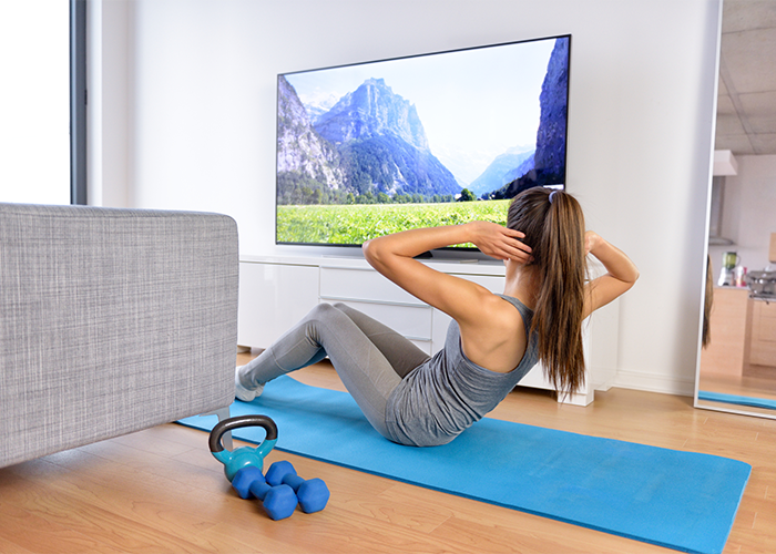 Woman doing crunches at home while watching TV.