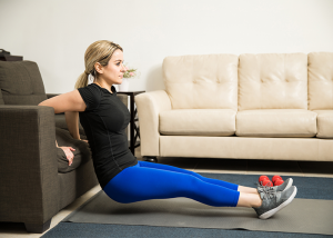 Women doing chair dips using her couch as part of a calisthenics workout.