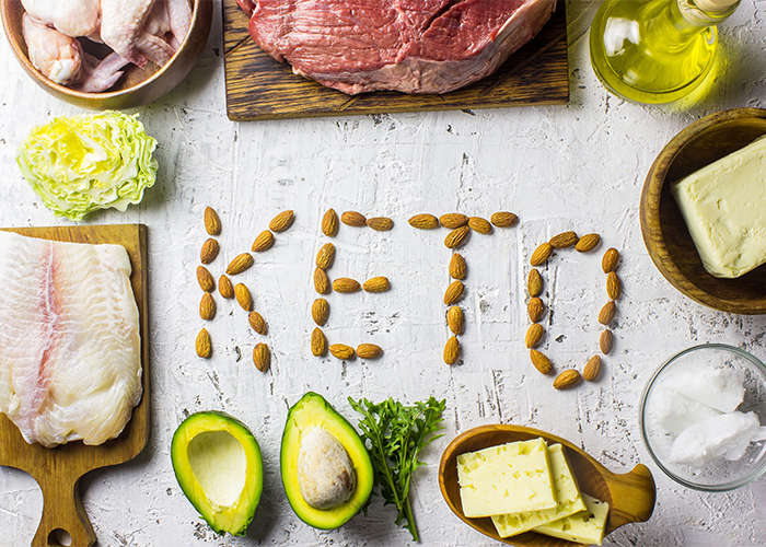 Typical low-carb foods eaten on the Keto diet surrounding almonds that spell out "KETO"