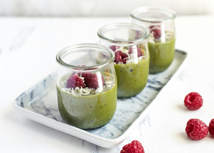 Cups of homemade avocado and white chocolate cream mousse topped with raspberries