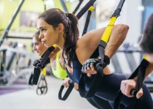woman working out on TRX machine as part of a HIIT workout