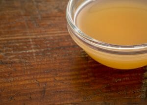 raw apple cider vinegar in a dish on a wooden table