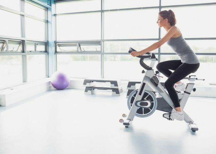 Woman on an exercise bike in a brightly lit gym