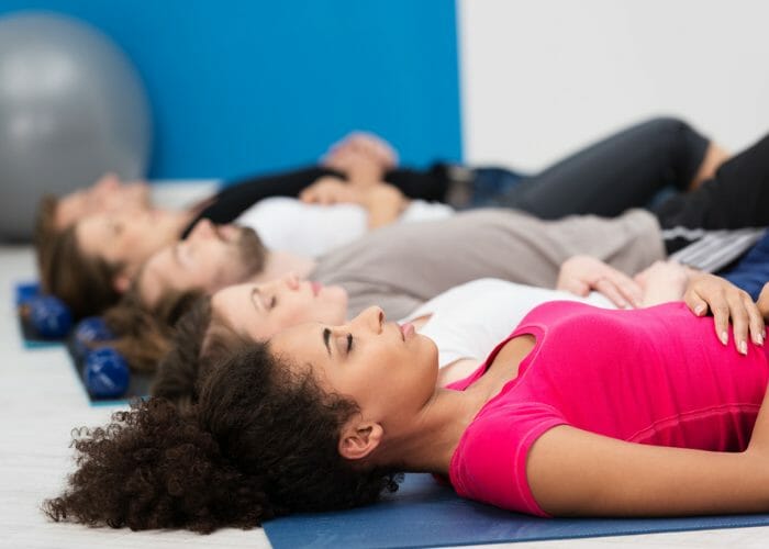 People laying on the floor in a gym doing breathing exercises