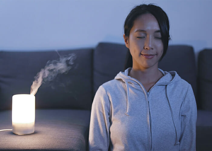 Woman meditating with a diffuser with her eyes closed