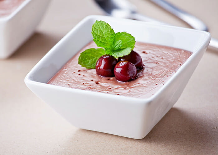 Homemade cherry vanilla pudding with avocado topped with cherries and mint.