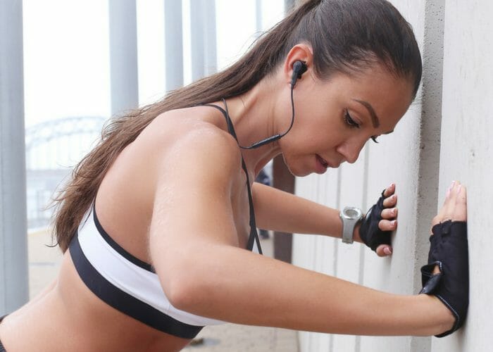 woman with earphones doing wall push up chest exercises