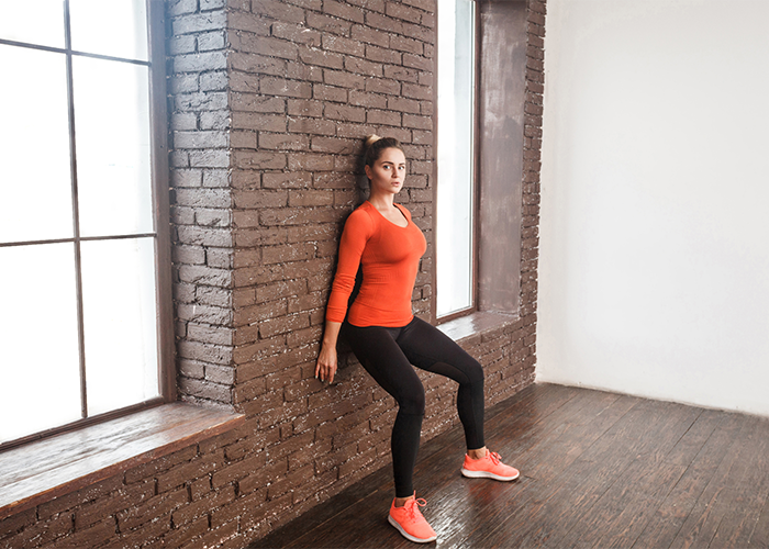 Woman performing wall sit core exercise 