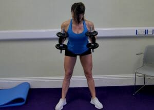 woman holding dumbbells doing standing triceps extensions