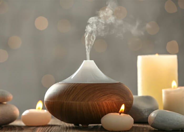 Essential oil blend diffuser for aromatherapy with essential oil candles surrounding it