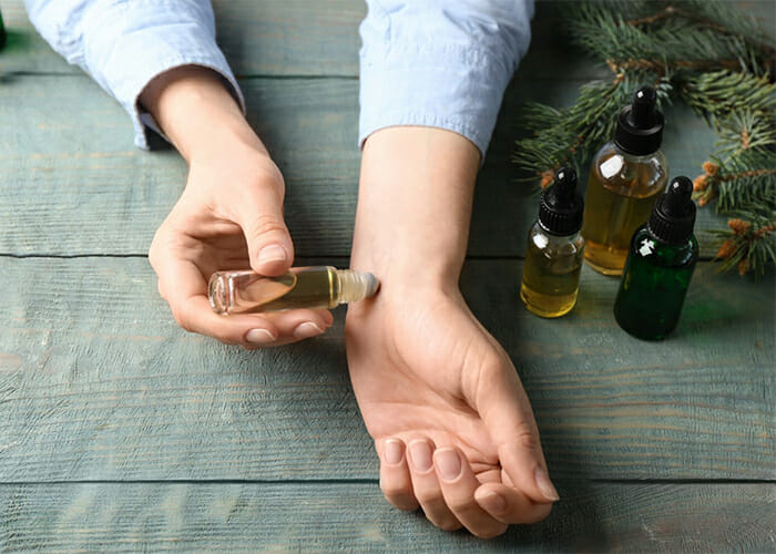 Woman using a homemade essential oil roll-on perfume diluted with coconut oil on her wrist