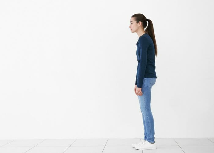 a girl standing upright with poor posture