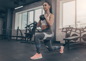 Fit young woman going goblet squat lunges in a gym