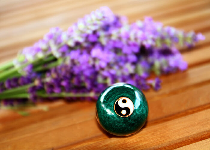 Focus on a green ball for relaxation with the Chinese yin and yang sign with sprigs of lavender in the background