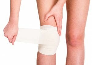 woman wrapping a bandage around her injured knee