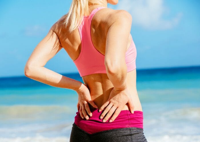 woman stretching her lower back before her workout on the beach