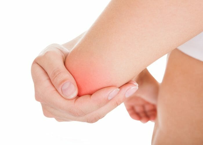 woman holding her strained elbow caused by a gym injury