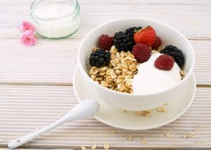 A bowl of homemade yogurt with oats, strawberries, raspberries, and blackberries. 