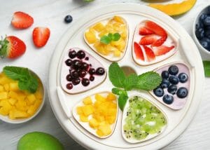 Top down view of yogurt maker with different fruit toppings on the yogurts