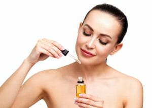 Woman applying a dropper of essential oils for sagging skin to her body