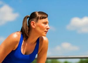 woman with a ponytail in a blue tank top getting ready to run