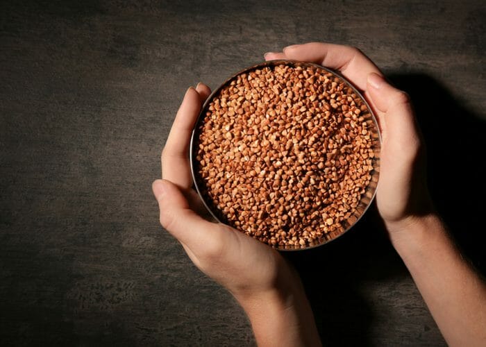 a person holding a bowl full of buckwheat grains