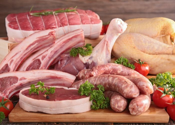 table filled with meat proteins such as chicken, beef, sausages, and pork