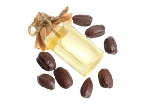 A bottle of jojoba essential oil for skin hydration surrounded by jojoba seeds