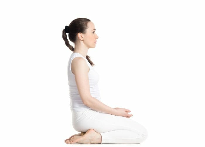 Woman dressed in white doing the rock pose during Kundalini yoga practice