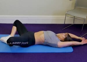 woman lying on an exercise mat doing butterfly sit ups to tone lower abs