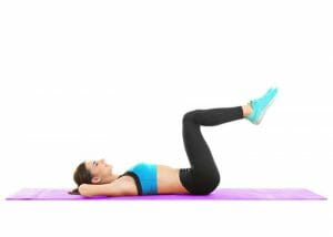 woman lying on an exercise mat on the floor doing heel touches for abs workout
