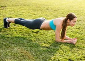 woman doing planks on a green lawn to tone lower abs