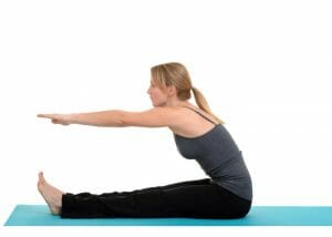 woman sitting on an exercise mat reaching for her toes