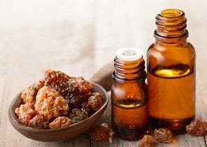 Bottles of myrrh essential oil for firmer skin next to a spoon filled with myrrh