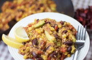 One pot vegan mexican quinoa plated on a white dish with lemon wedges on the side