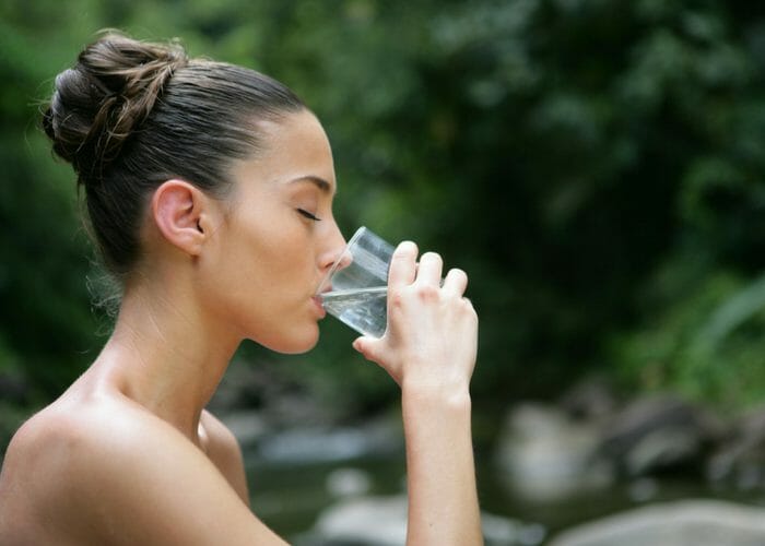 woman drinking a glass of water outdoors
