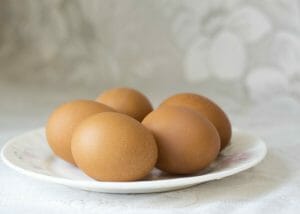 5 brown eggs on a white plate