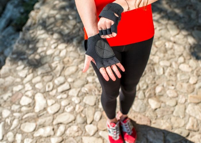 Woman in red fitness top and red shoes putting on parkour gloves