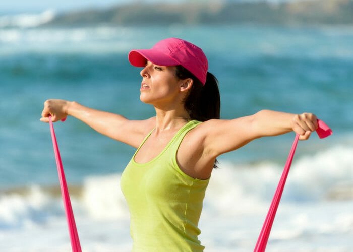 woman working out on the beach with a resistance band