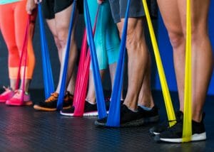 a row of people standing on colorful resistance bands