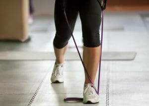 woman doing resistance band training exercises on a tile floor
