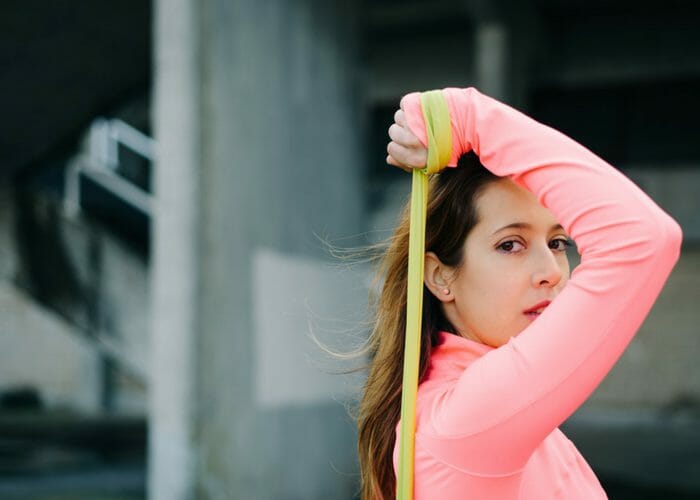 a woman in pink sweater doing stretches with a resistance band