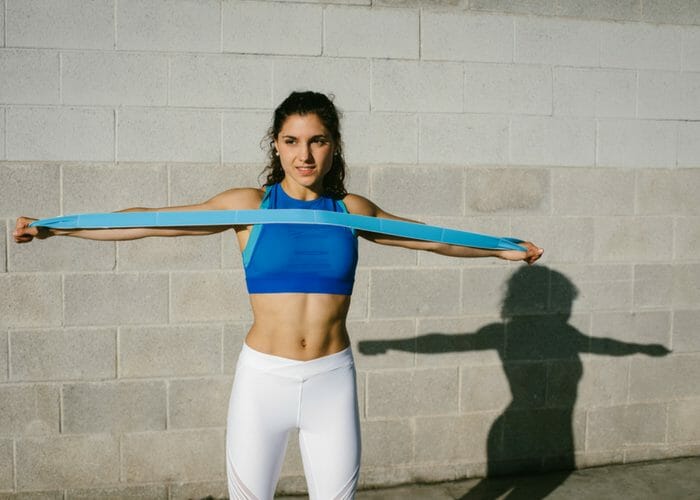 fit woman stretching a resistance band across her chest with both hands