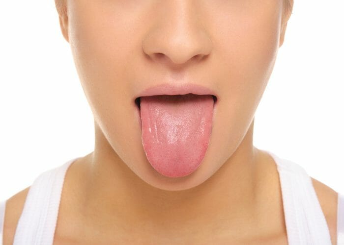 Close up of a woman's face with her tongue sticking out to do the breathing exercise simhasana