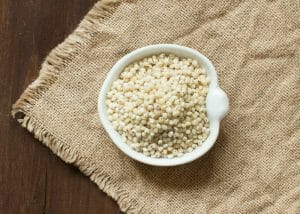 sorghum grains in a white bowl on a brown tablecloth