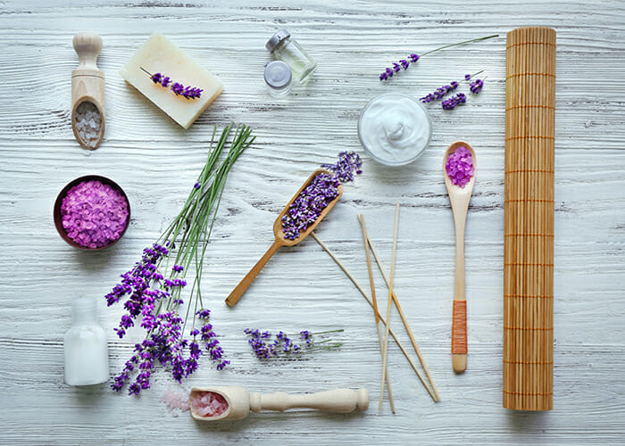 Flat lay of lavender essential oil spa products such as bath salts, moisturizing creams, and soap 