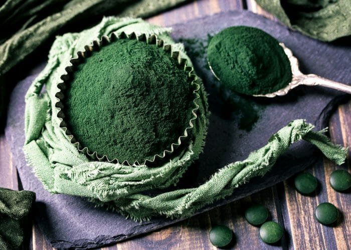a cupcake tin and tablespoon filled with spirulina powder