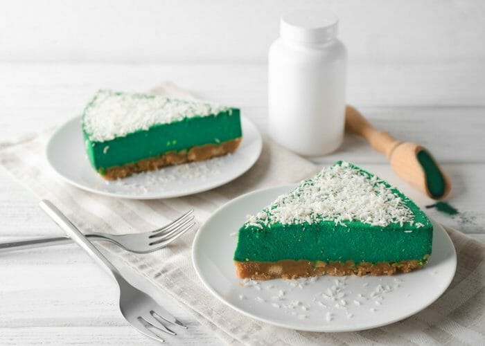 2 slices of green spirulina cheesecake on white plates