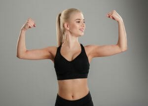 blonde woman in black sports bra flexing her biceps 